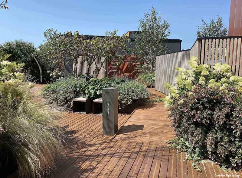 Une terrasse en bois accueillie par des masses végétales généreuses qui dessinent un paysage vivant et enveloppant